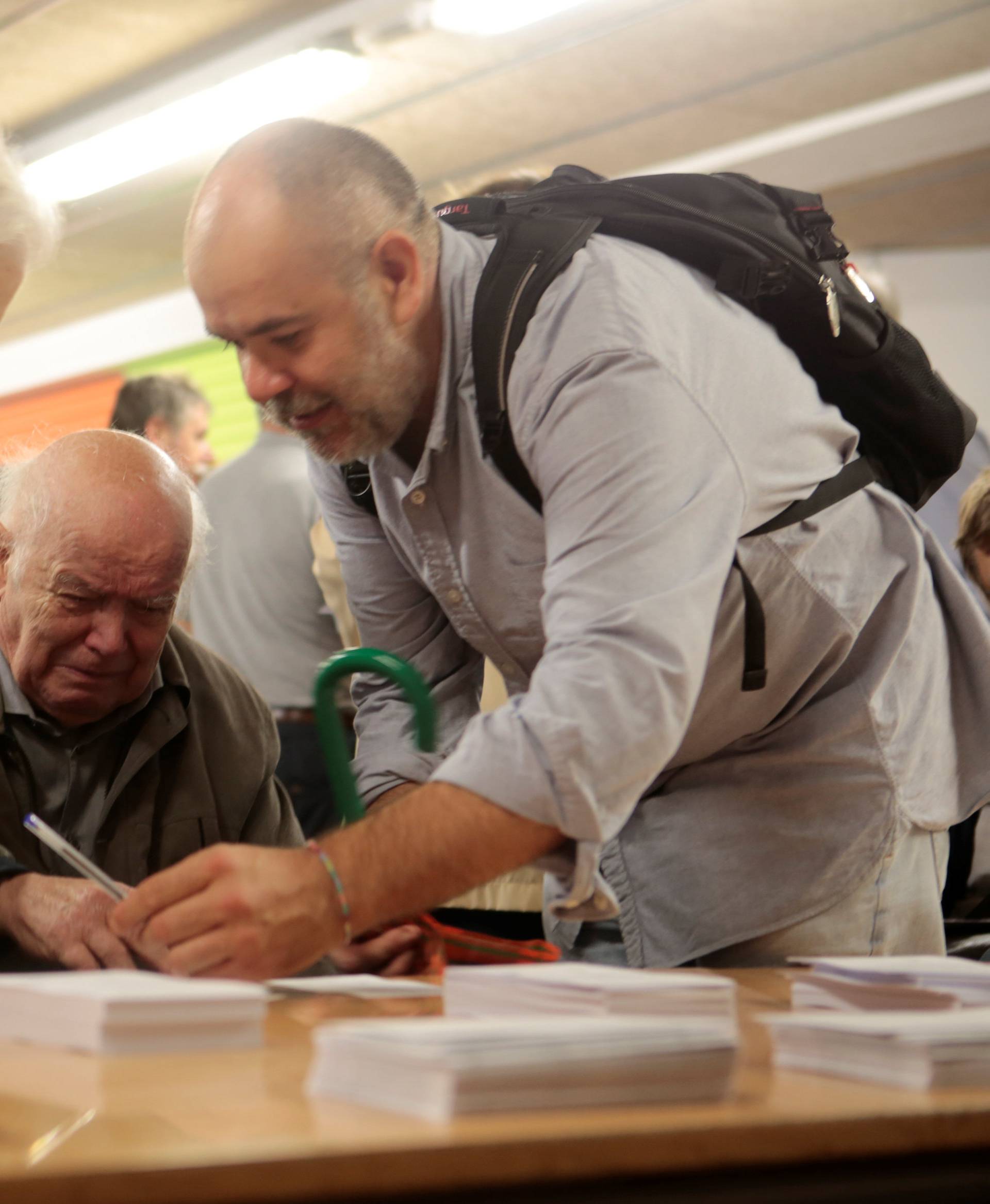 An old man reacts as he picks up a ballot inside a polling station for the banned separatist referendum in Barcelona