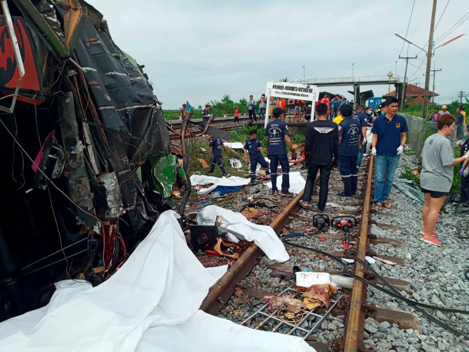 Rescue workers stand at the crash site where a train collided with a paseengers bus in Chacheongsao province in central Thailand