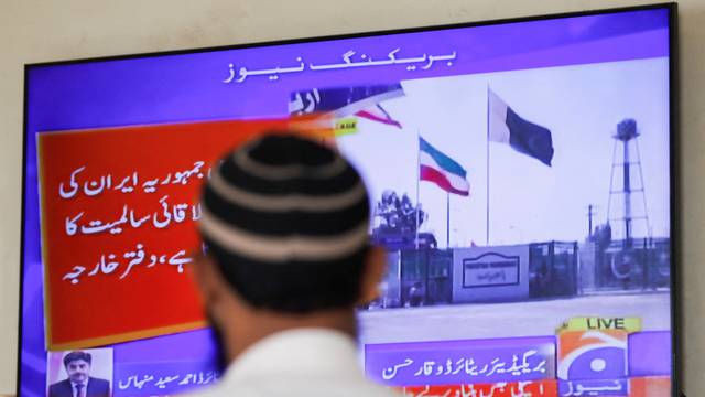 Man looks on television screen, after the Pakistani foreign ministry said the country conducted strikes targeting separatist militants inside Iran, in Karachi