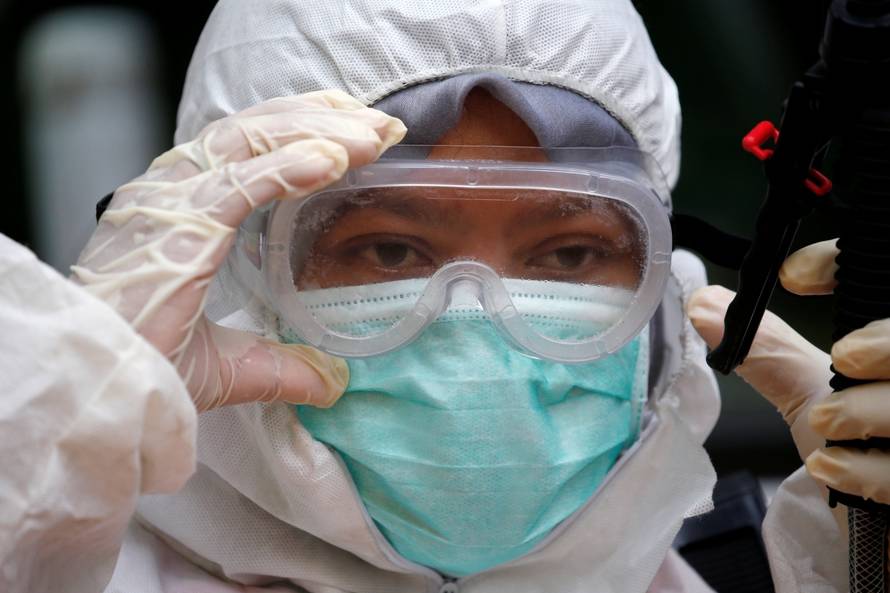 A volunteer from Indonesia's Red Cross puts on protective gear while preparing to spray disinfectant at a school closed amid the spread of coronavirus in Jakarta