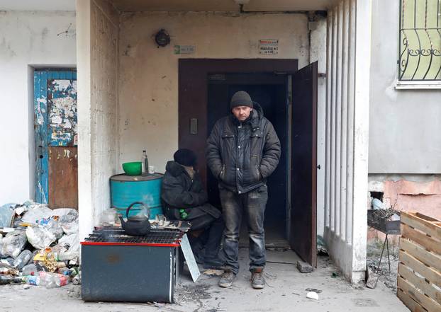 Local residents are seen outside a residential building in the besieged city of Mariupol