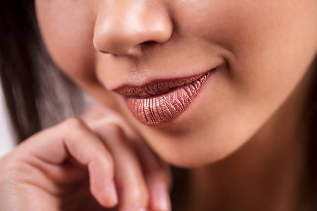 Closeup of beautiful smiling dark-skinned women, macro, detail shot. Shiny brown lipstick, lip gloss, cosmetics, makeup.