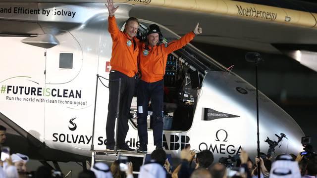 Pilots Andre Borschberg and Bertrand Piccard celebrate their arrival on Solar Impulse 2, a solar powered plane, at an airport in Abu Dhabi, UAE
