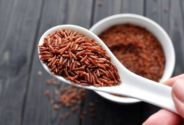 hand holdind a spoon with uncooked red rice