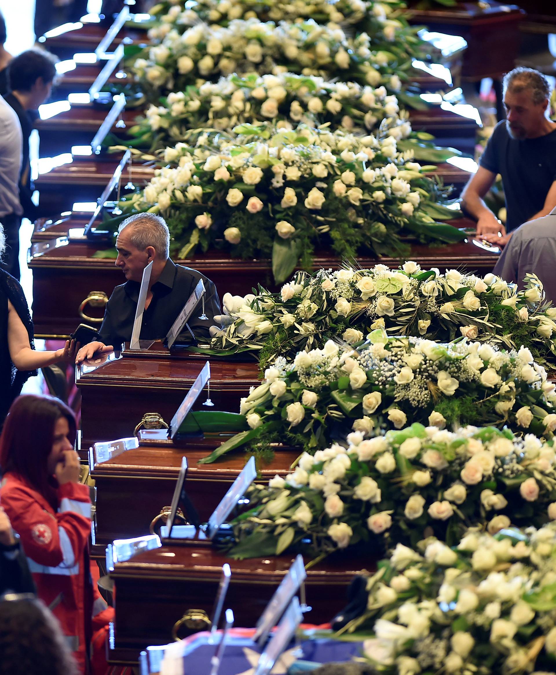 People mourn next to the coffins containing bodies of victims of the Genoa bridge collapse, at the Genoa Trade Fair and Exhibition Centre in Genoa