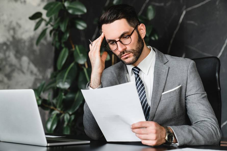 Caucasian,Stressed,Businessman,Checking,Documents,While,Working,On,Laptop,Online