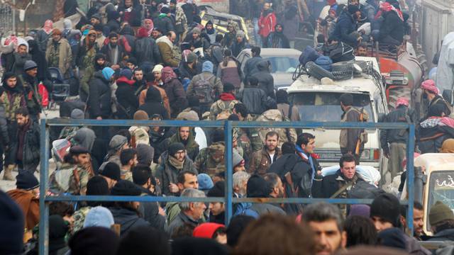 Rebel fighters and civilians gather as they wait to be evacuated from a rebel-held sector of eastern Aleppo