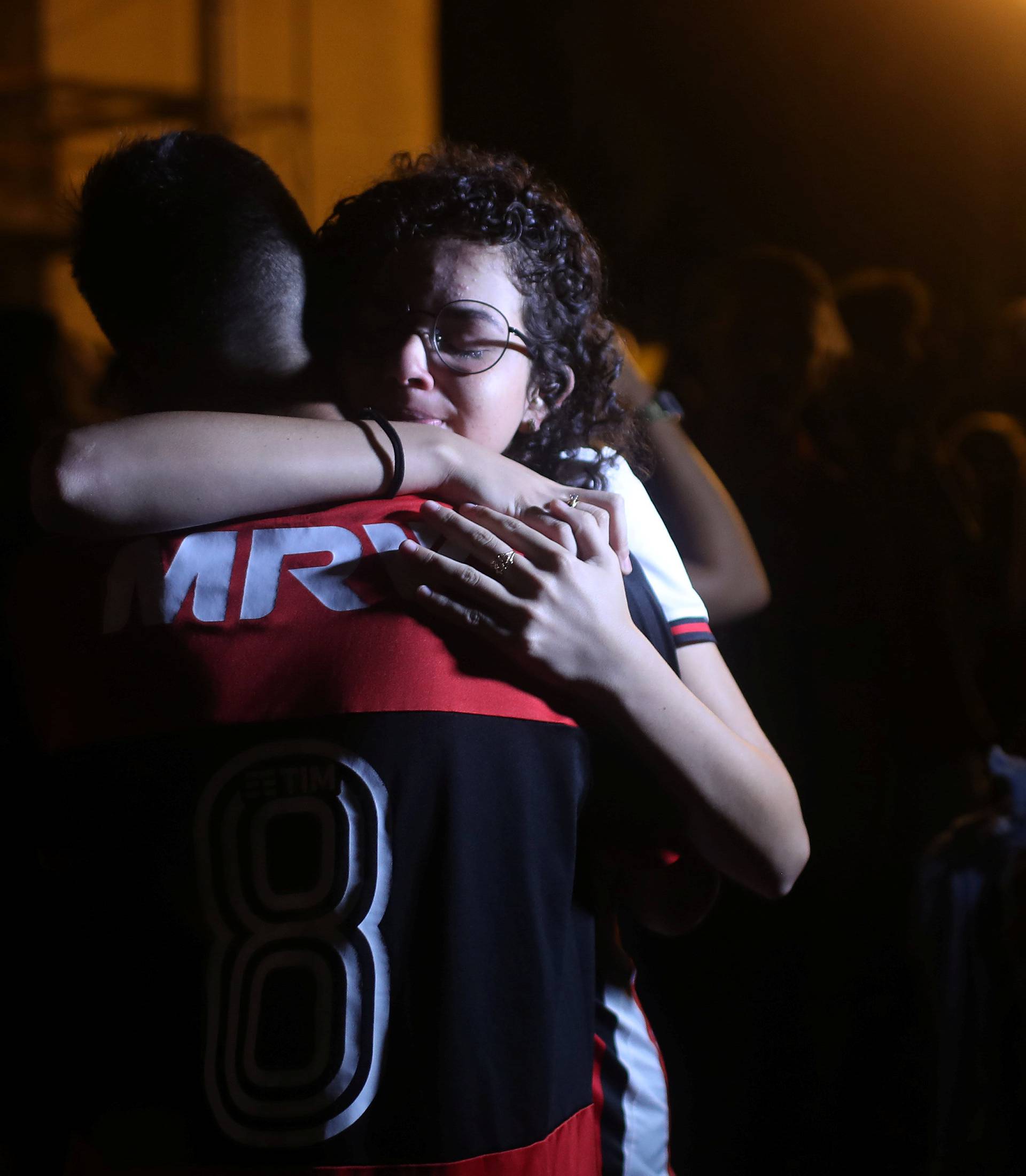A supporter embraces Flamengo youth soccer player Pereira fter a mass in memory of the victims of the club's training center deadly fire in Rio de Janeiro