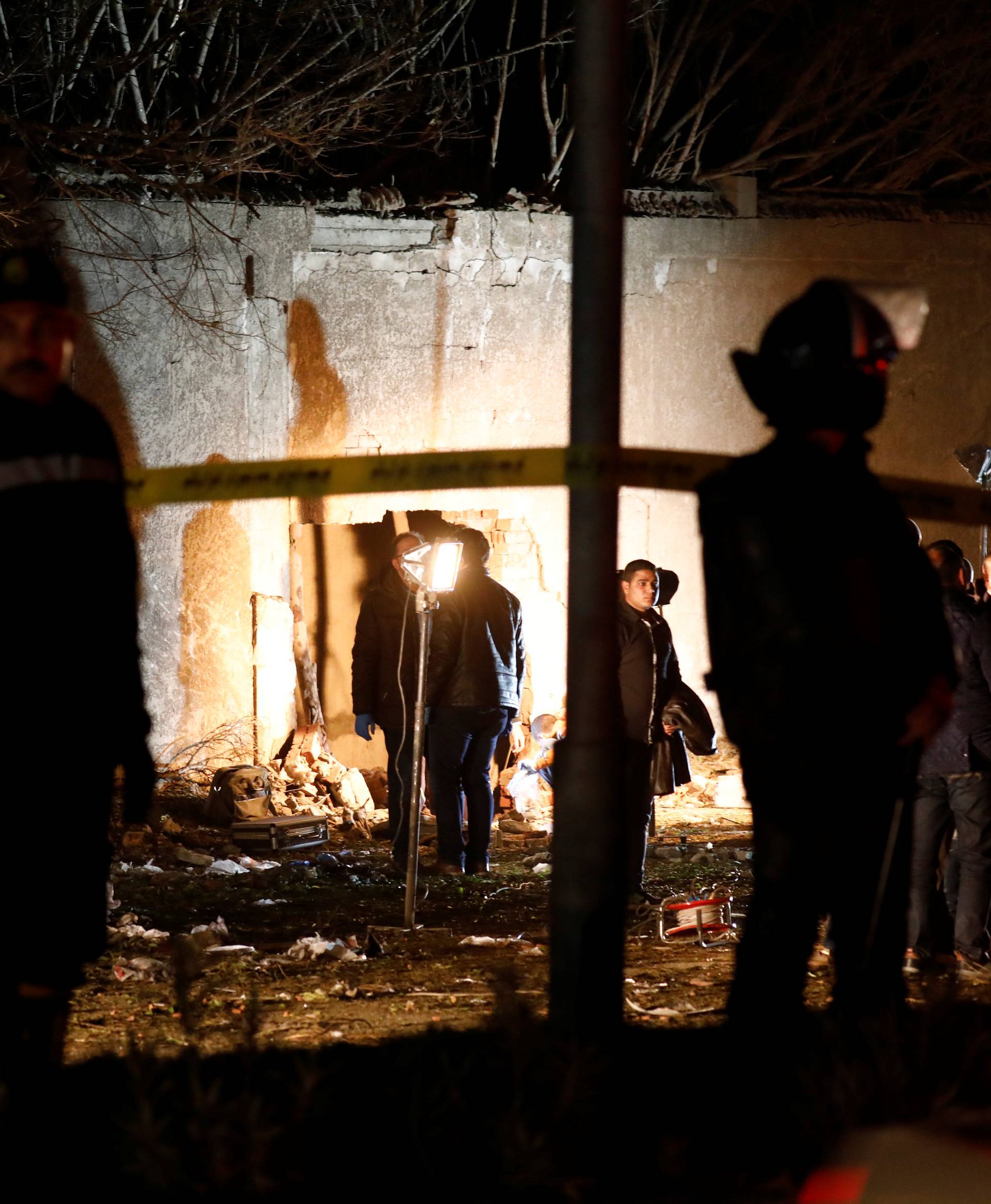 Police officers inspect a scene of a bus blast in Giza