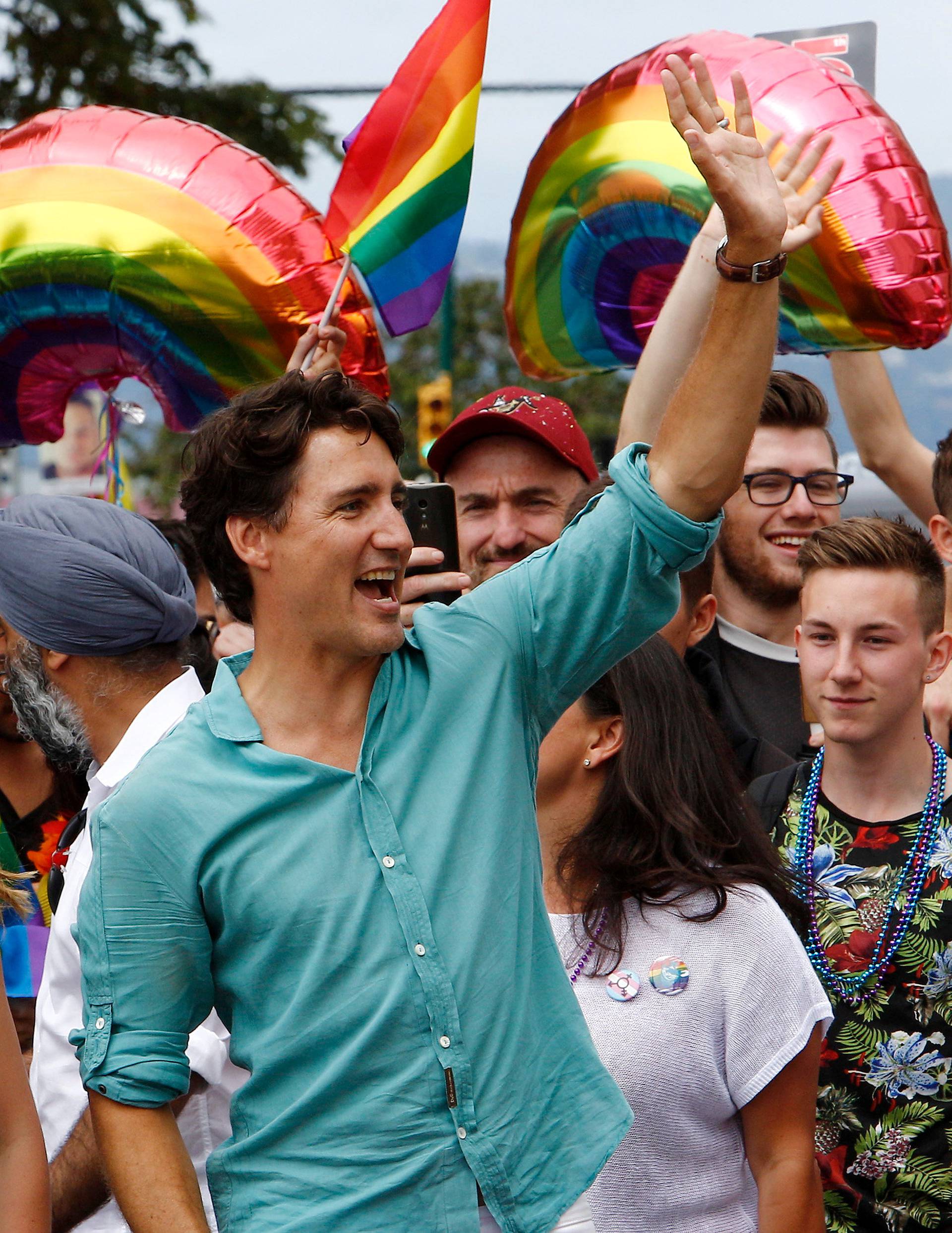 Canada's Prime Minister Justin Trudeau waves to a crowd next to his wife Sophie GrÃ©goire Trudeau while walking in the Vancouver Pride Parade in Vancouver