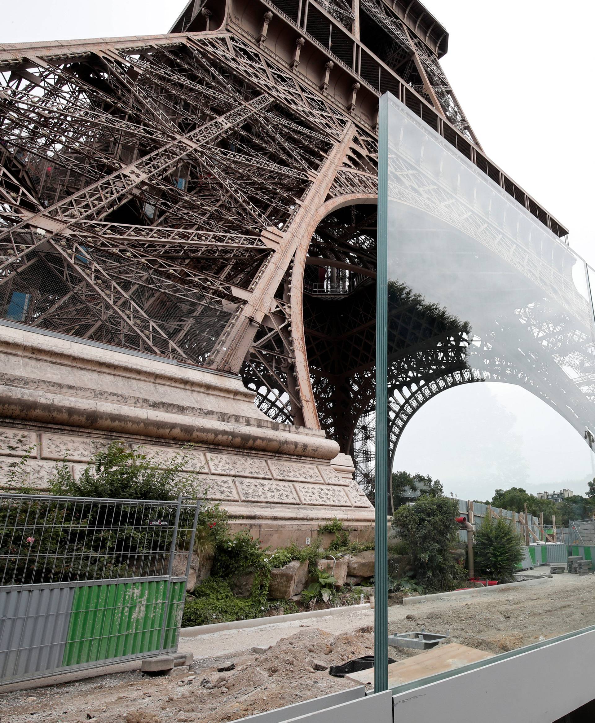 A member of the media makes images of the new glass security fence which is under construction around the Eiffel Tower in Paris