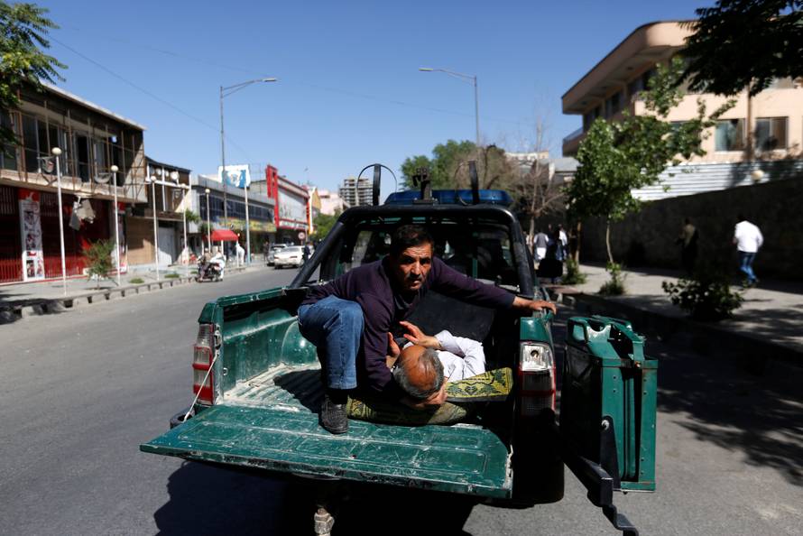 A man holds an injured outside a hospital after a blast in Kabul, Afghanistan