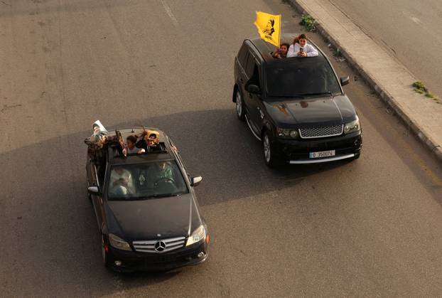 People in vehicles hold up items depicting former Hezbollah leaders Hassan Nasrallah and Hashem Safieddine, after a 10-day ceasefire between Lebanon and Israel went into effect, in Sidon
