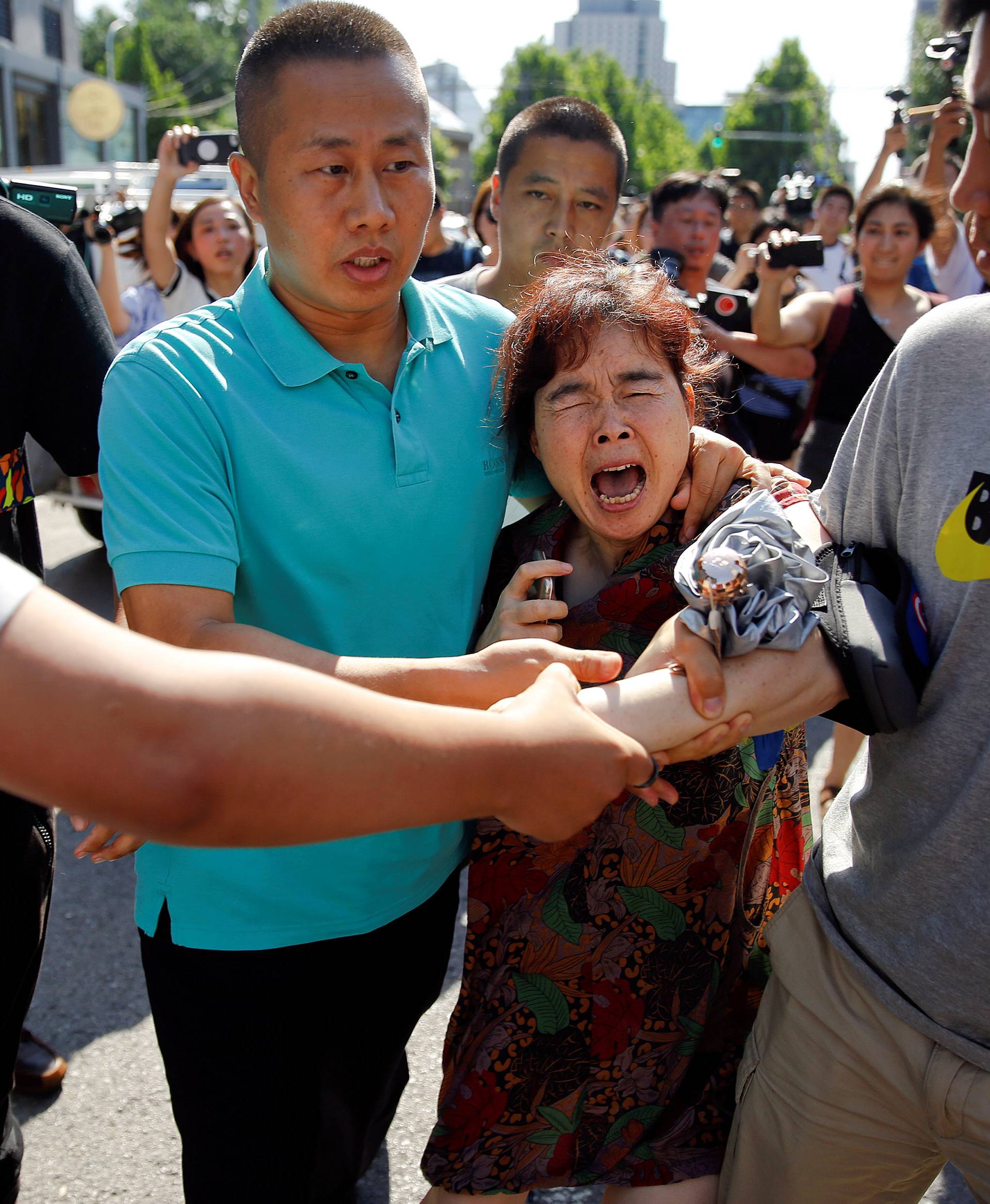 A woman is detained by security personnel outside the U.S. embassy in Beijing