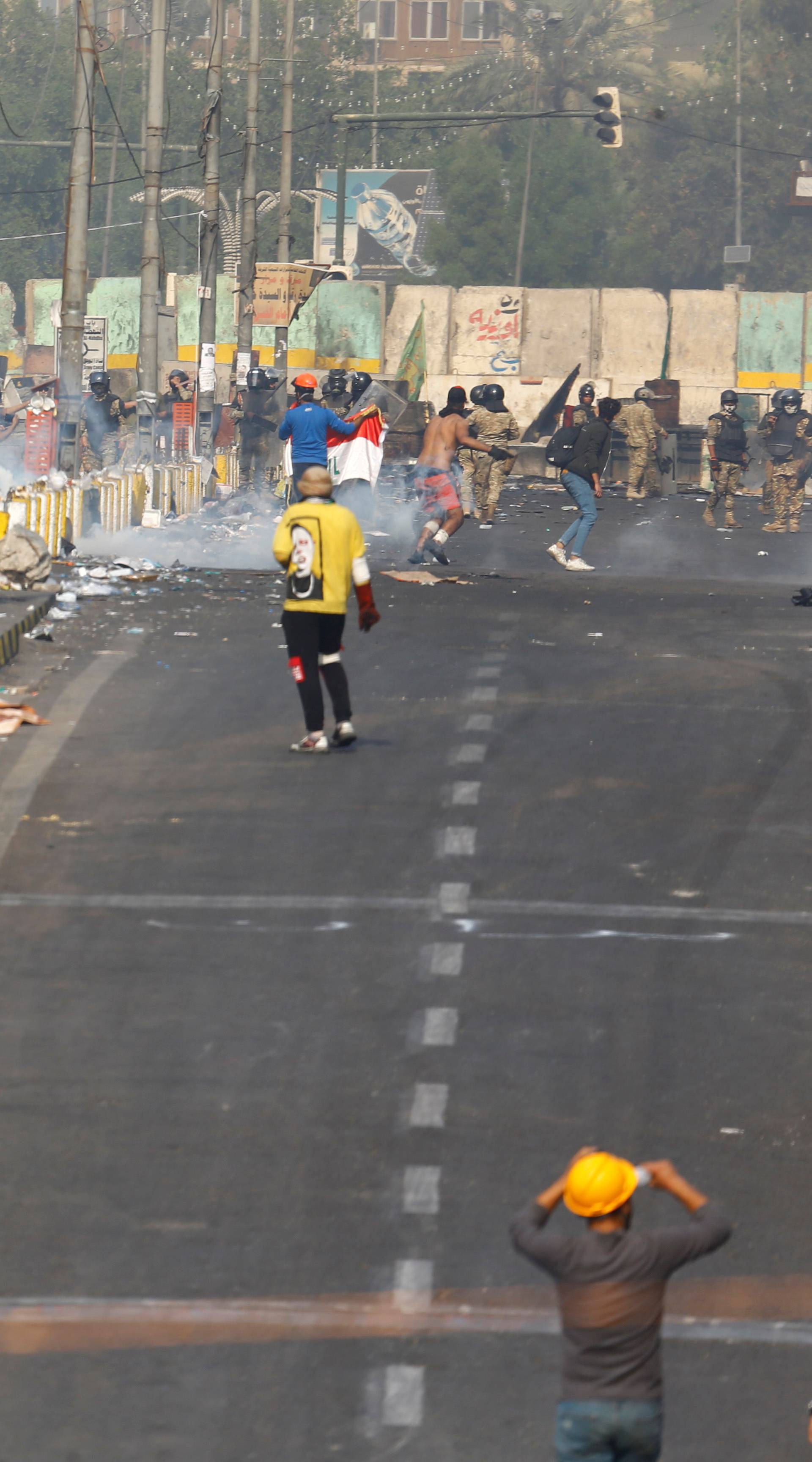 Iraqi demonstrators clash with members of Iraqi security forces during ongoing anti-government protests in Baghdad