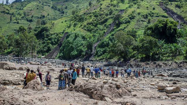 Congolese civilians gather after the death of their family members following rains that destroyed buildings and forced aid workers to gather mud-clad corpses into piles in the village of Nyamukubi