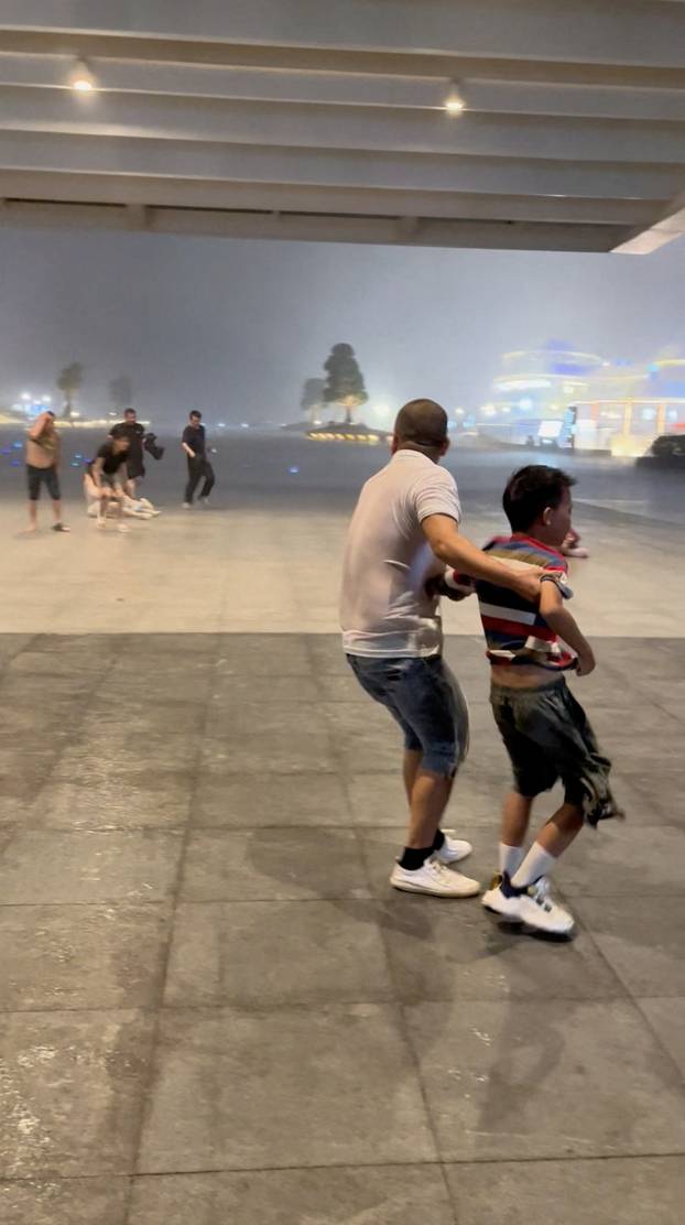 People seek shelter from wind near Zhuhai Opera house building, during typhoon Wipha, in Zhuhai