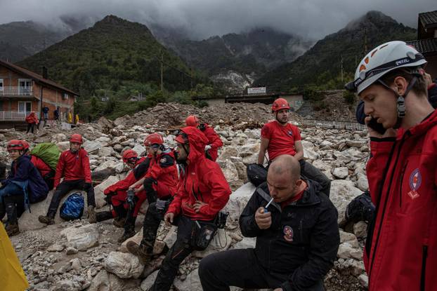 Rescue workers sit among debris following a landslide in the flooded village of Donja Jablanica