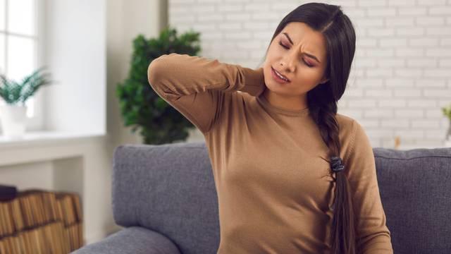 Woman rubbing her neck, suffering from pinched nerve, osteochondrosis or whiplash