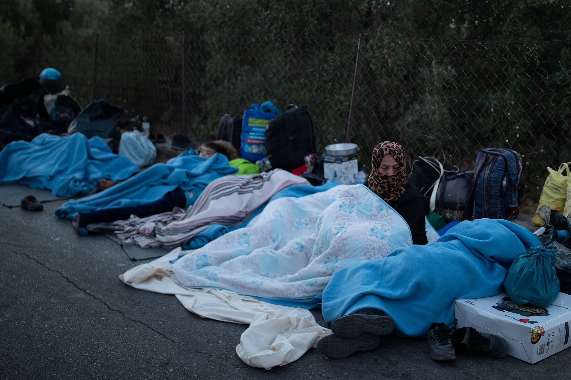 Refugees and migrants sleep on a road following a fire at the Moria camp on the island of Lesbos