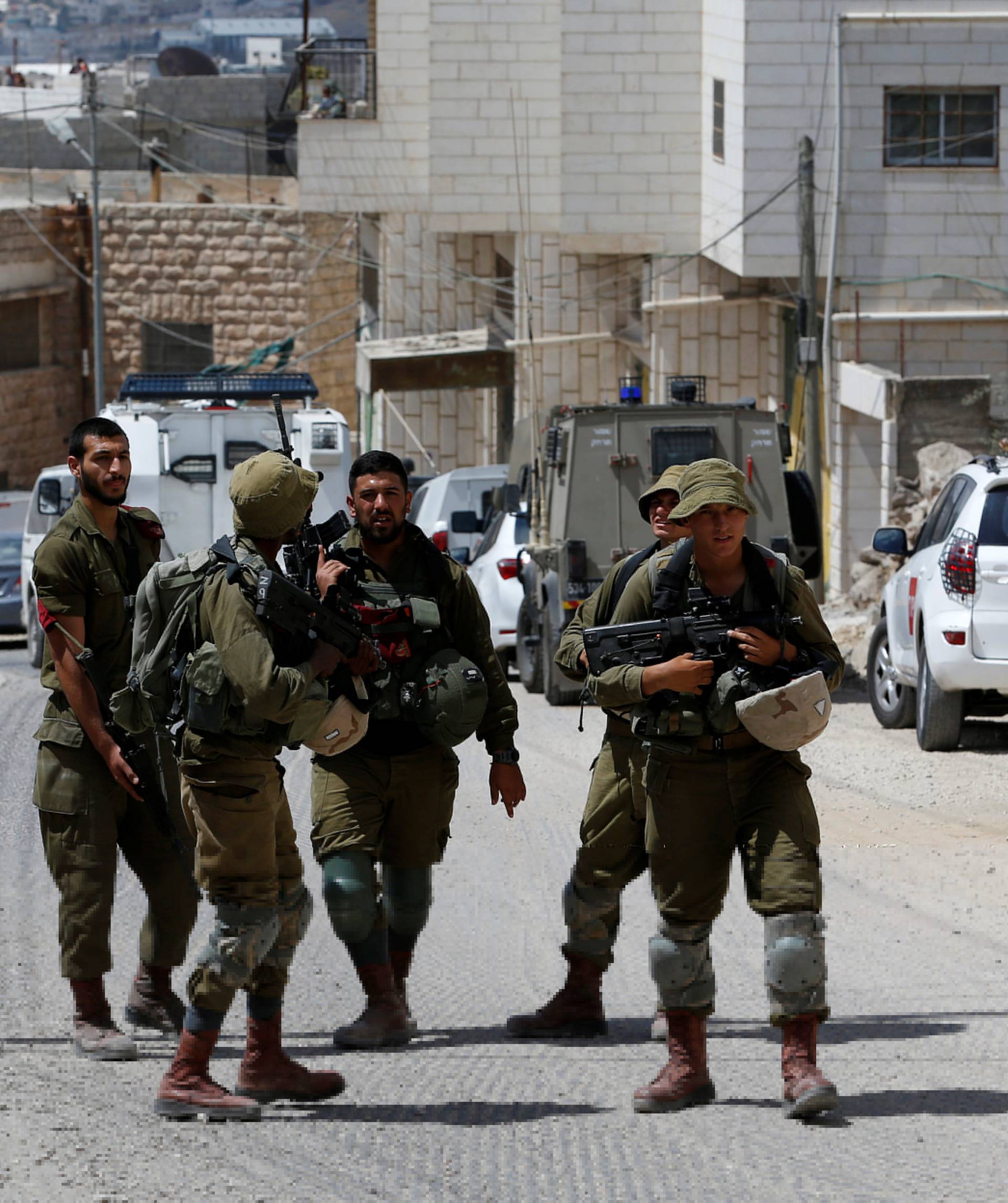 Israeli soldiers stand at the scene of attempted car ramming attack, in Hebron in the occupied West Bank