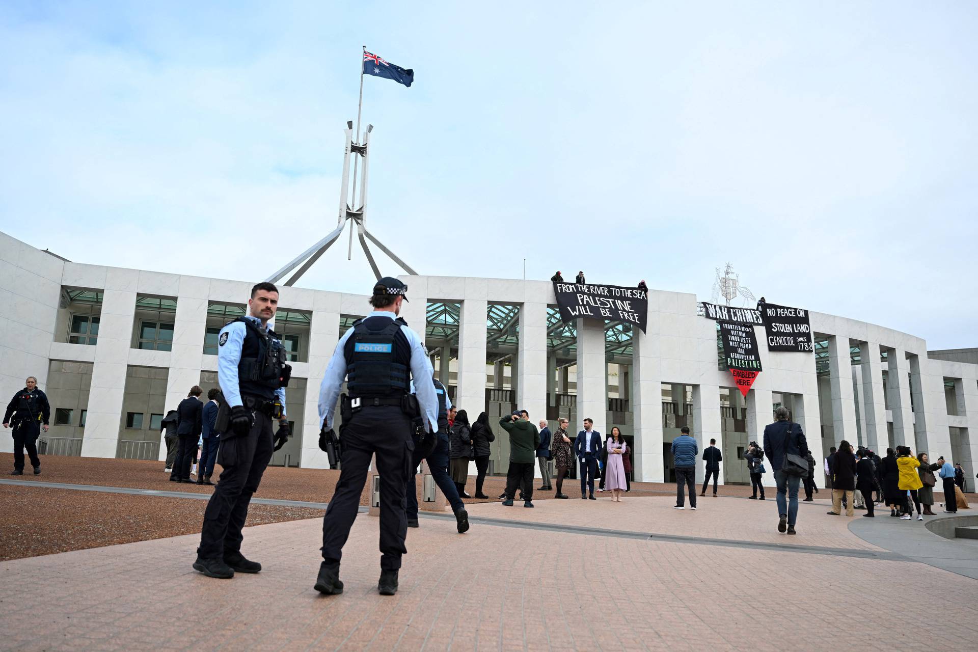 Pro-Palestinian protesters hang banners from the top of Parliament House, in Canberra