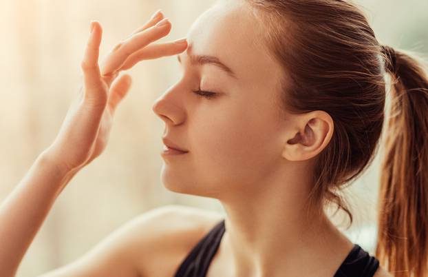 Young woman massaging third eye chakra