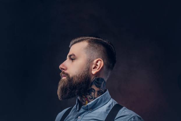 Profile of a handsome old-fashioned hipster in a blue shirt and suspenders.