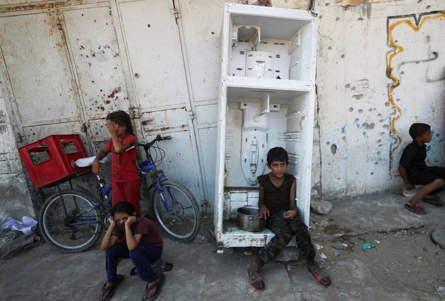 Palestinians wait to receive food from a charity kitchen, amid a hunger crisis, in Gaza City