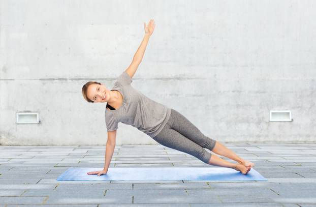 woman making yoga in side plank pose on mat