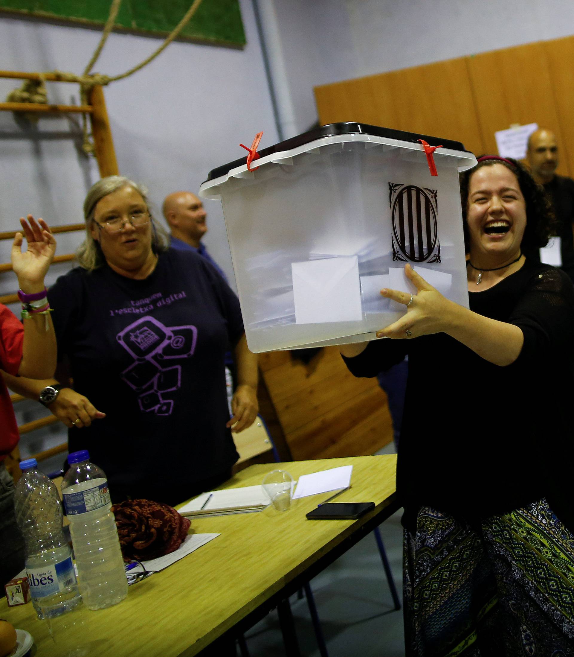 Poll workers lift a ballot box in celebration after polls closed at a polling station for the banned independence referendum in Barcelona