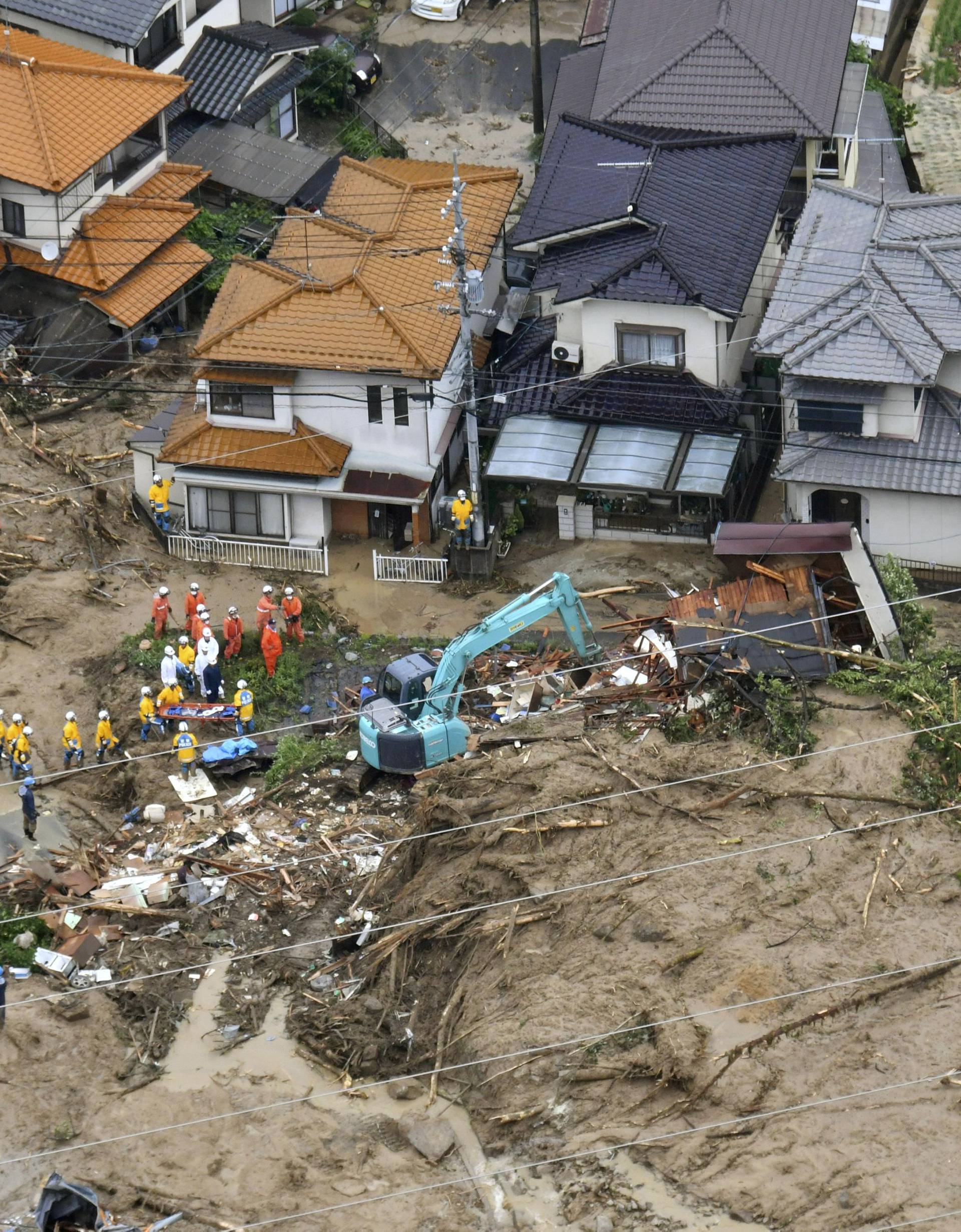 Rescue workers are seen next to houses damaged by a landslide following heavy rain in Hiroshima