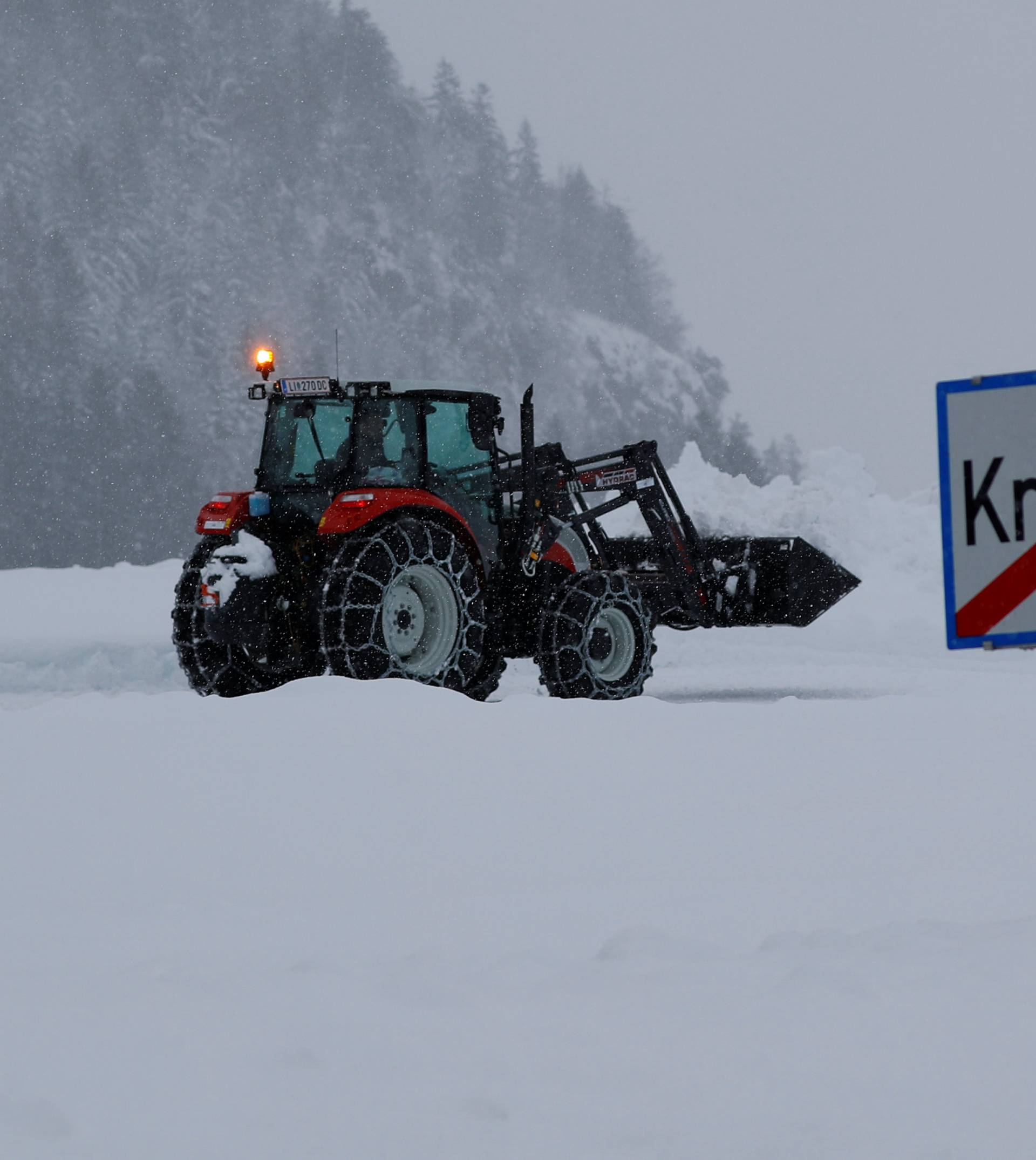 A tractor shovels snow on an icy road after heavy snowfall in Knoppen