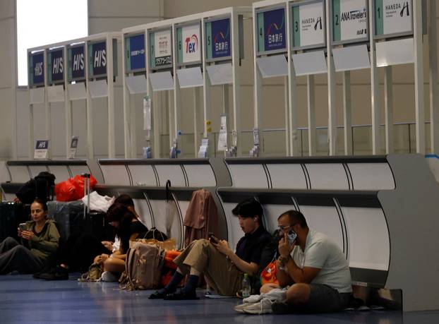 Passengers rest at Haneda Airport as many flights are delayed and cancelled due to Typhoon Dujuan, in Tokyo