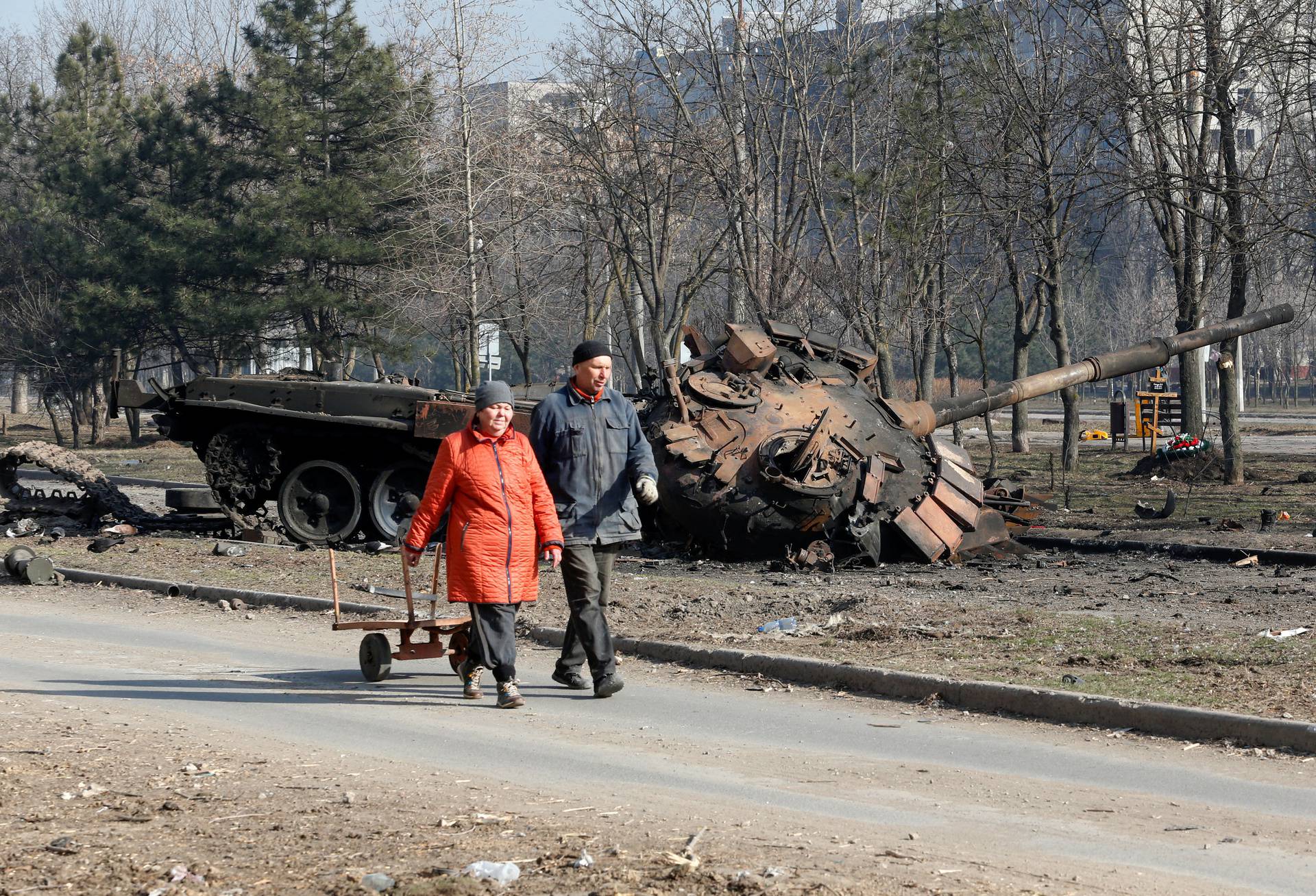 People walks past a tank destroyed in fighting during Ukraine-Russia conflict, in the besieged southern port of Mariupol