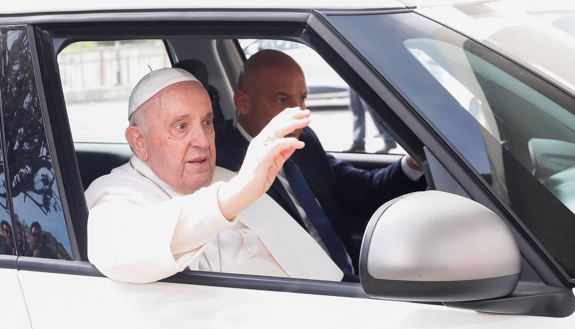 Pope Francis waves from a car as he leaves Rome's Gemelli hospital in Rome