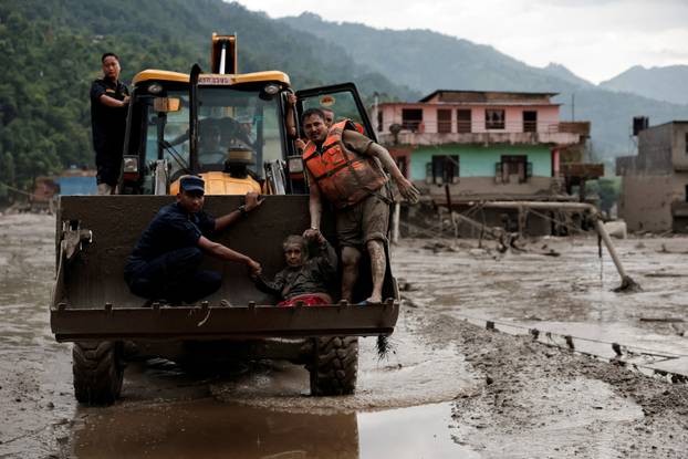 A survivor is transported to a safer place in a JCB following a flash flood at Trishuli, Nepal