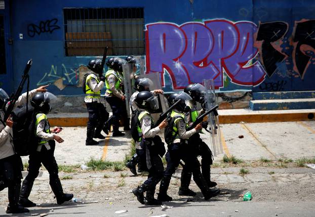 Riot police take position while clashing with opposition demonstrators during the so-called "mother of all marches" against Venezuela