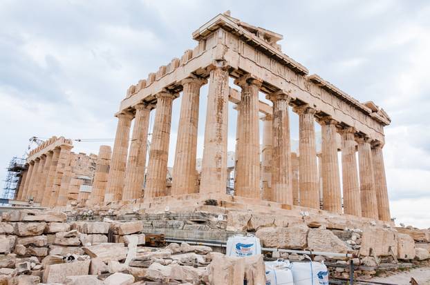 The famous Parthenon on Acropolis hill under reconstruction surrounded by scaffolding and standing big construction crane behind the temple