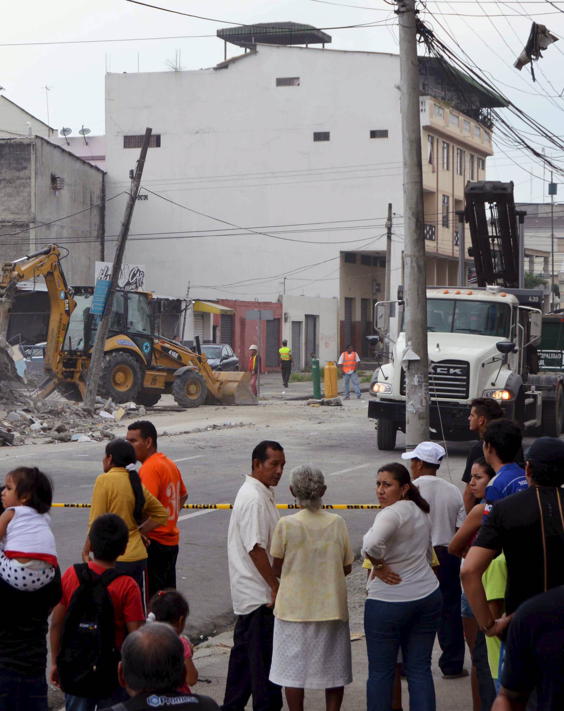 People look as a bulldozer removes the debris of a collapsed house after an earthquake struck off the Pacific coast, in Guayaquil