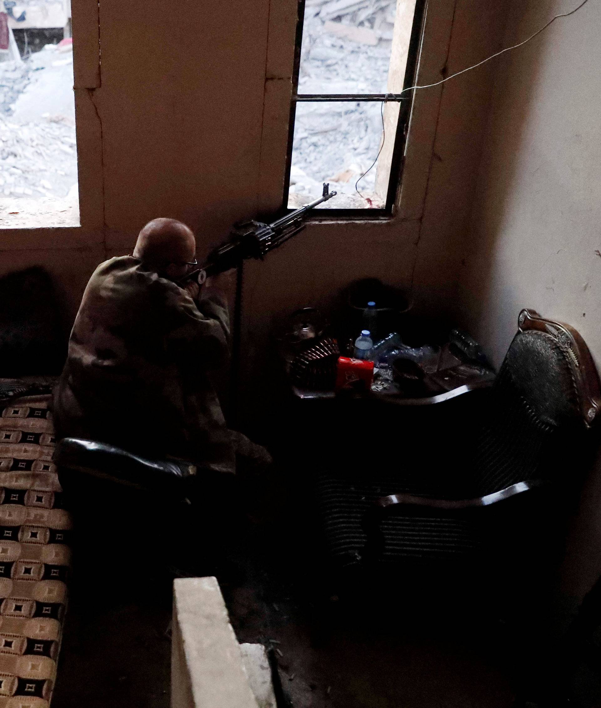 An American volunteer fighter of Syrian Democratic Forces fires a machine-gun during a battle with Islamic State militants at the frontline in Raqqa