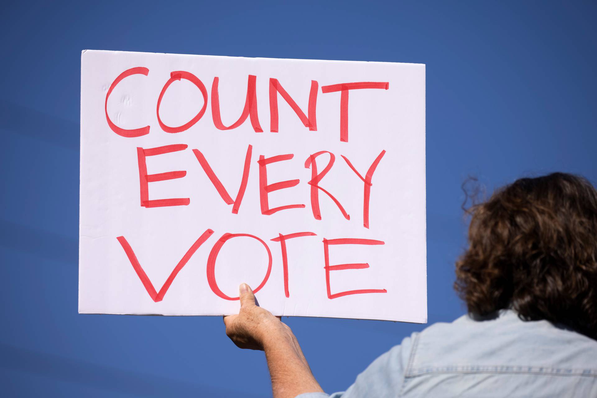 A demonstrator from protect the results coalition protests against efforts to not count all the votes in the general election as they demonstrate in Poway, California