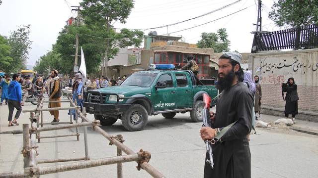 Taliban fighters stand guard at the site of an explosion in Kabul