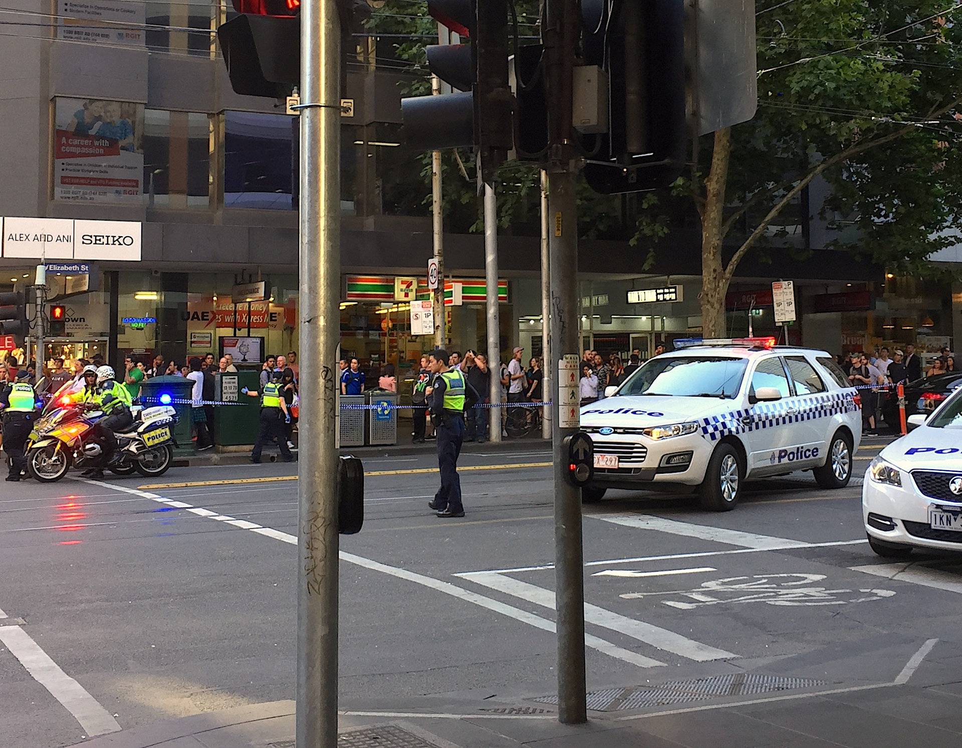 Police officers secure the area as members of the public stand behind police tape after the arrest of the driver of a vehicle that ploughed into pedestrians at a crowded intersection near the Flinders Street train station in central Melbourne