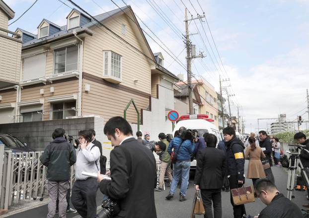 Members of the media gather in front of an apartment building where media reported nine bodies were found in Zama