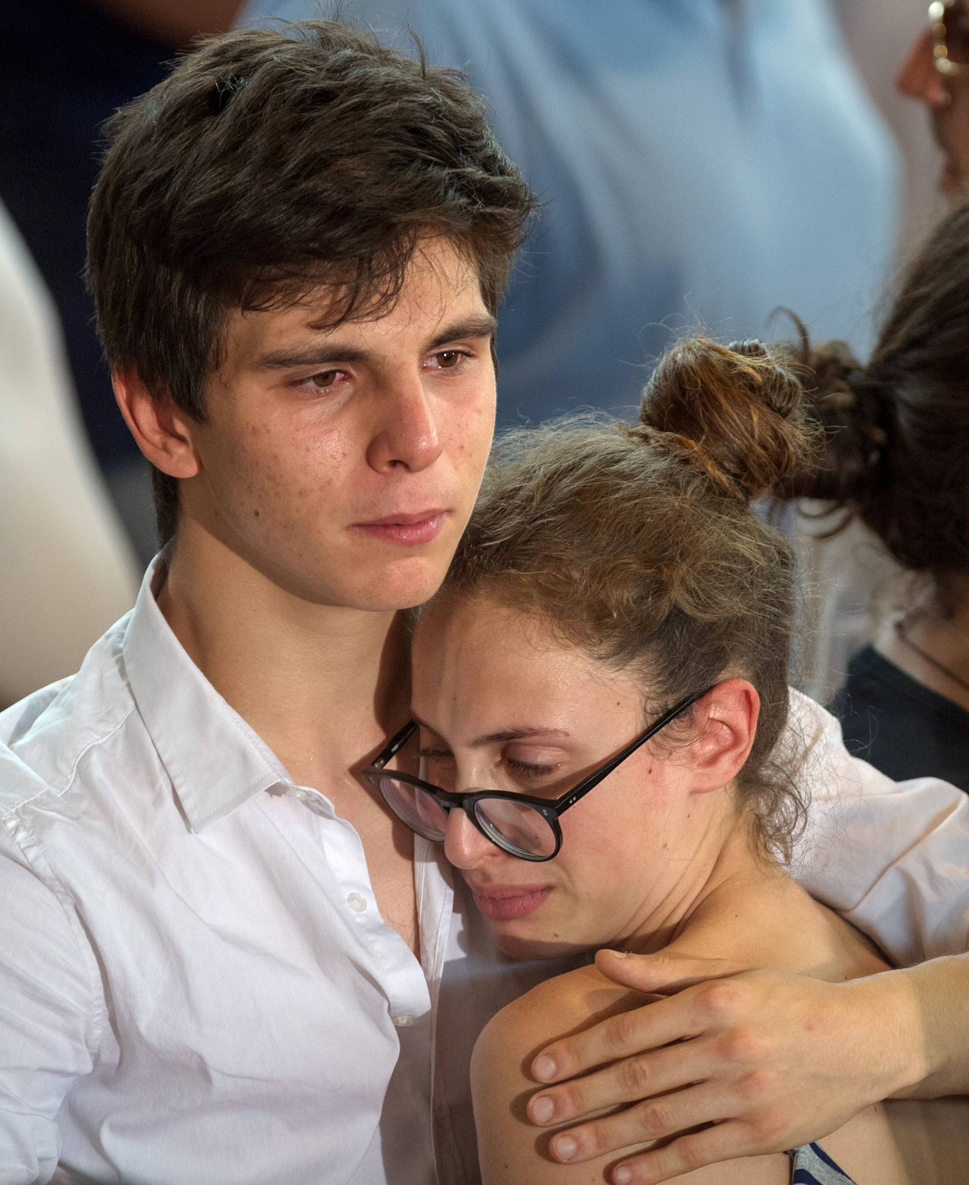 A man hugs a woman after a funeral service for victims of the earthquake inside a gym in Ascoli Piceno, Italy
