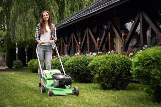 Front,View,Of,Pretty,Young,Smiling,Woman,Using,Lawn,Mower