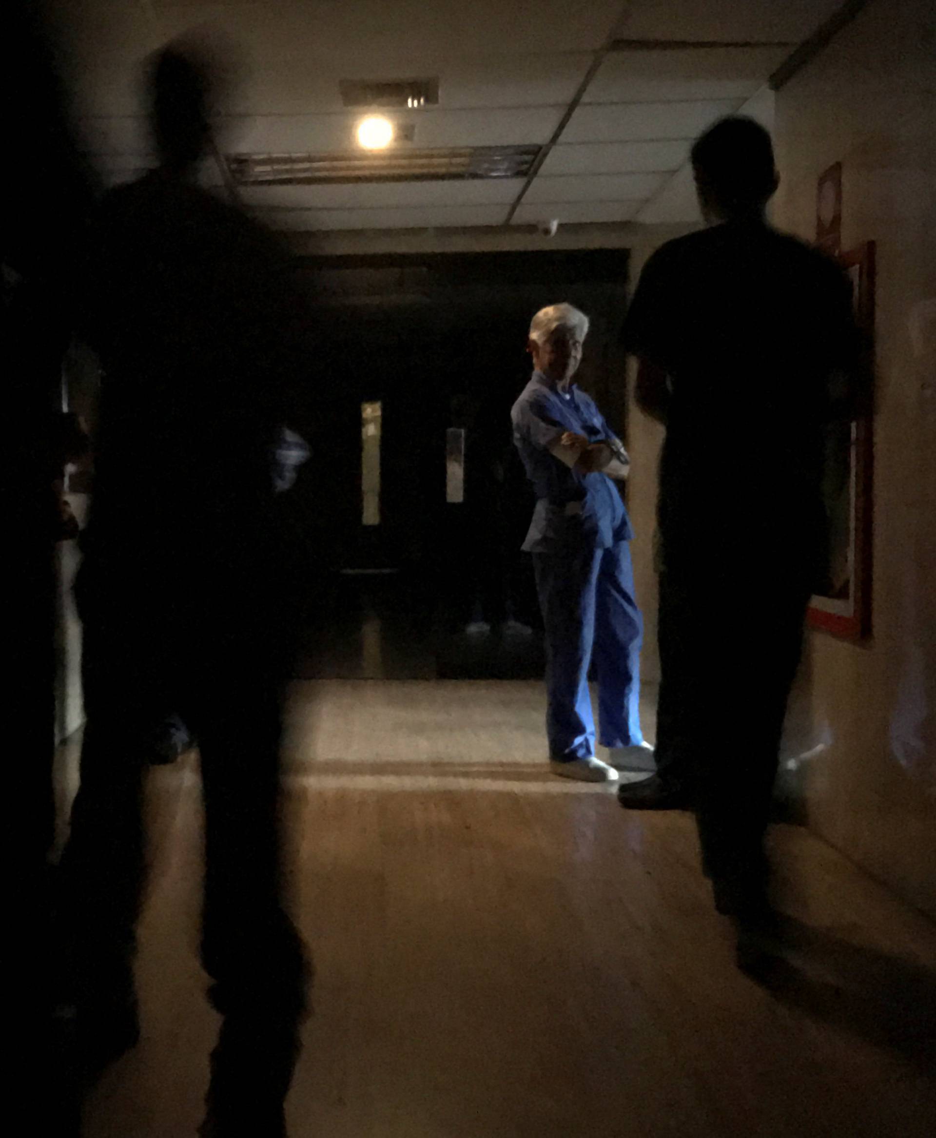 People wait at the emergency area of a clinic during a blackout in Caracas