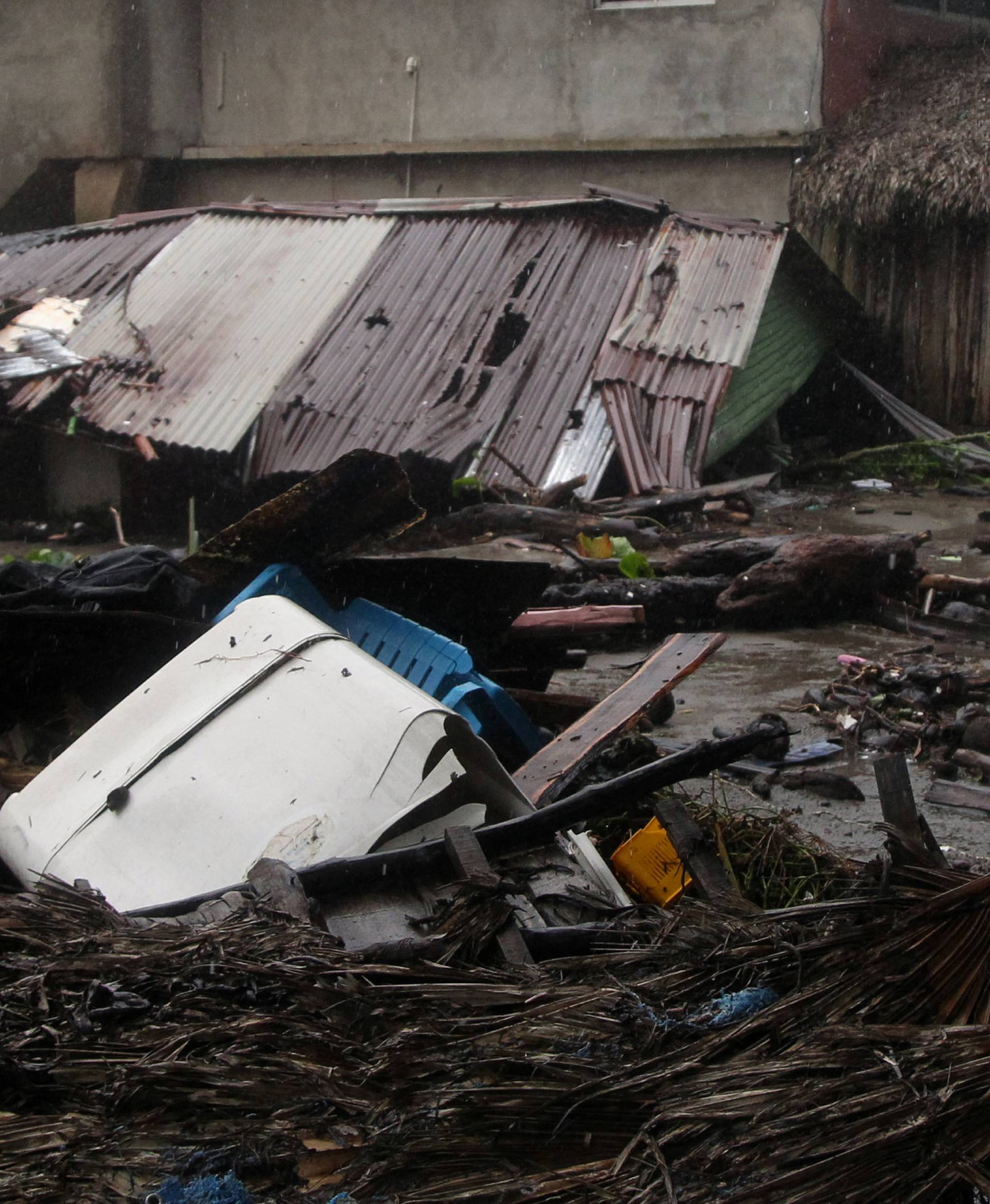 People walk past debris as Hurricane Irma moves off from the northern coast of the Dominican Republic, in Nagua