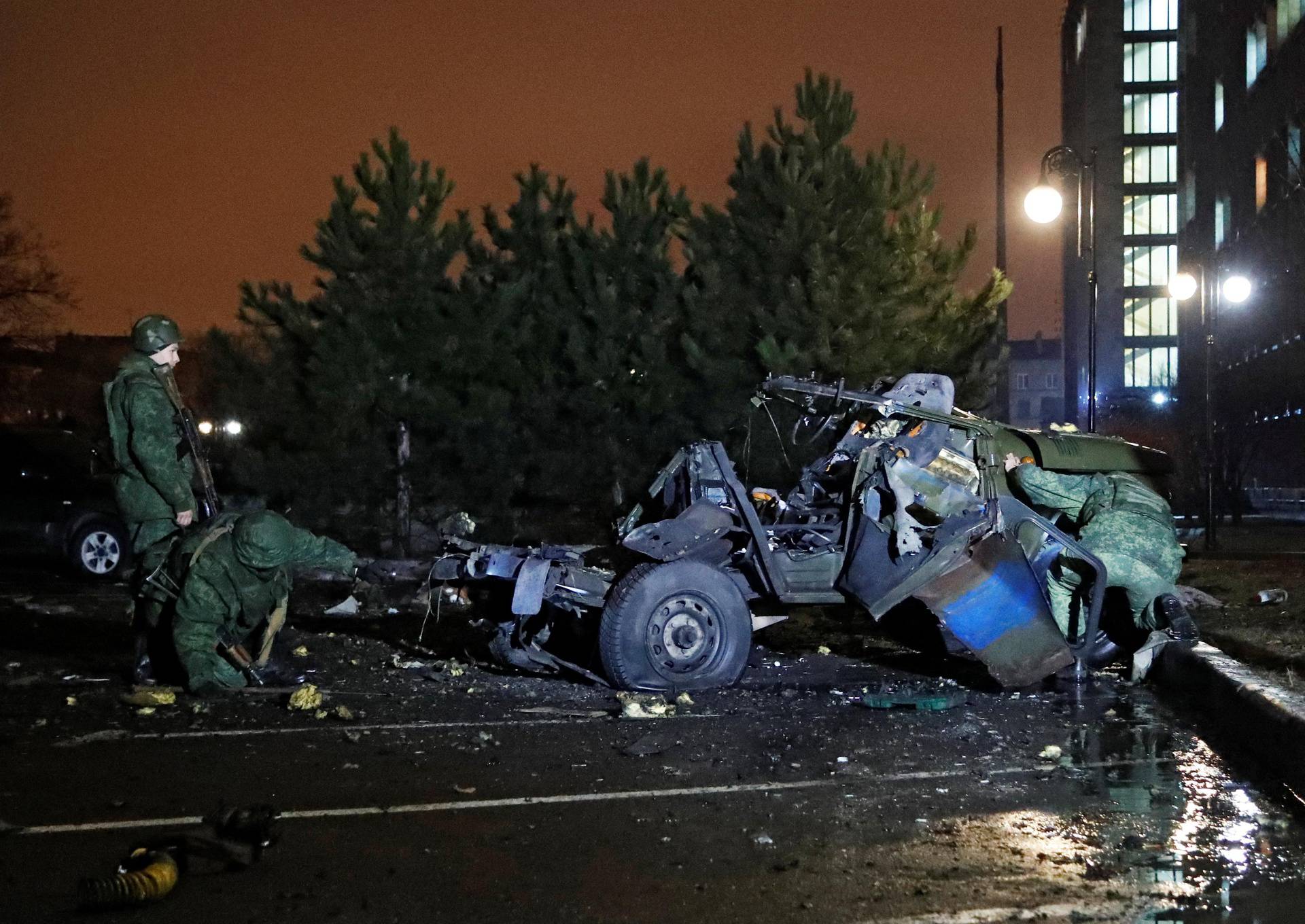 Specialists inspect a wreckage of a car that according to the local authorities was blown up in Donetsk